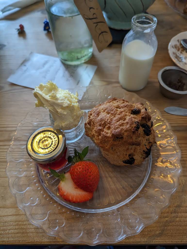 A customer's photograph at Mr H's: a scone with cream, jam and strawberry on a glass plate